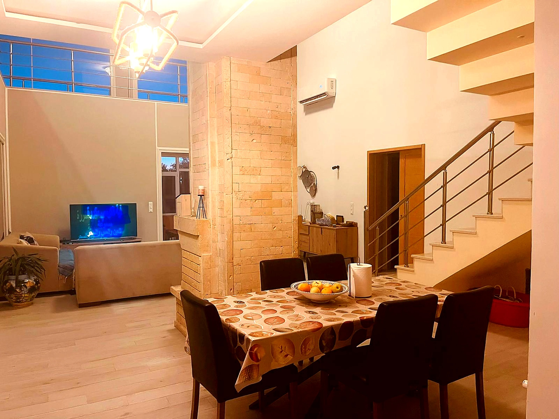 Open plan dining and living area with stone feature wall and staircase