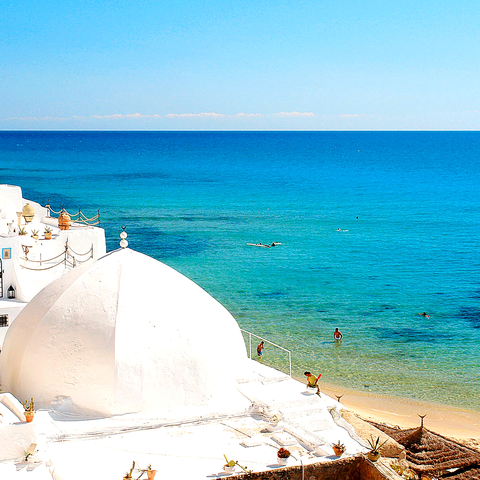 Traditional white domed architecture beside the turquoise sea