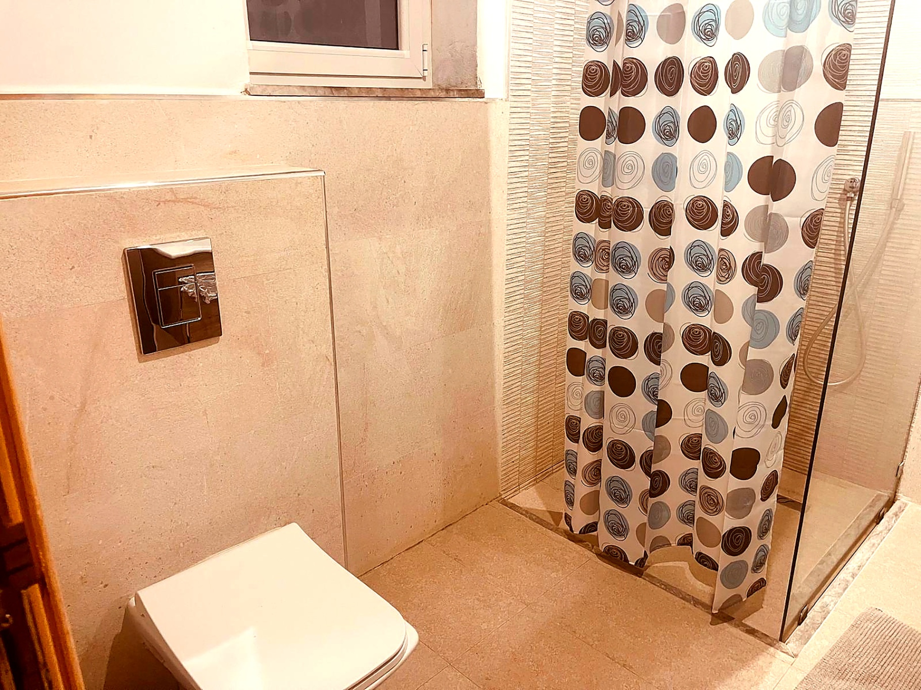 Guest bathroom in beige stone tiling with shower