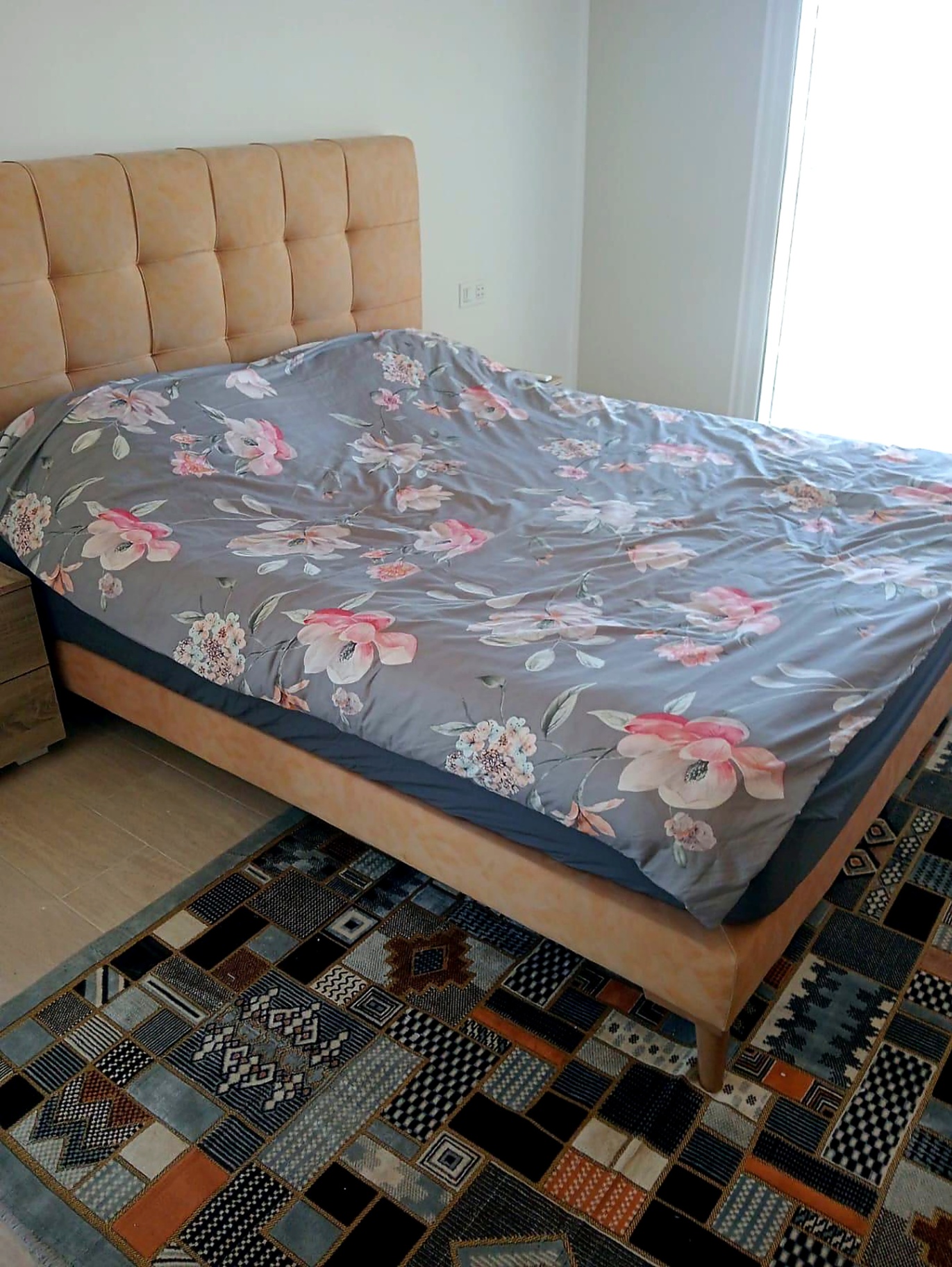 Bright double bedroom with tufted headboard and Berber rug