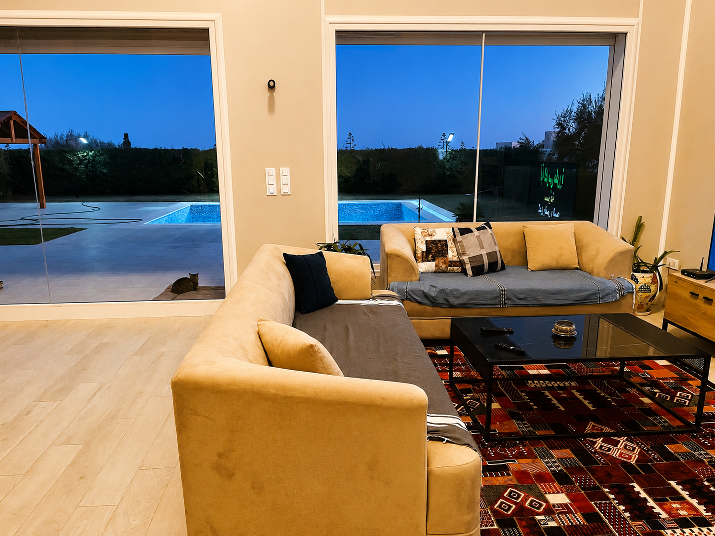 Living room at dusk with sliding glass doors onto the lit swimming pool