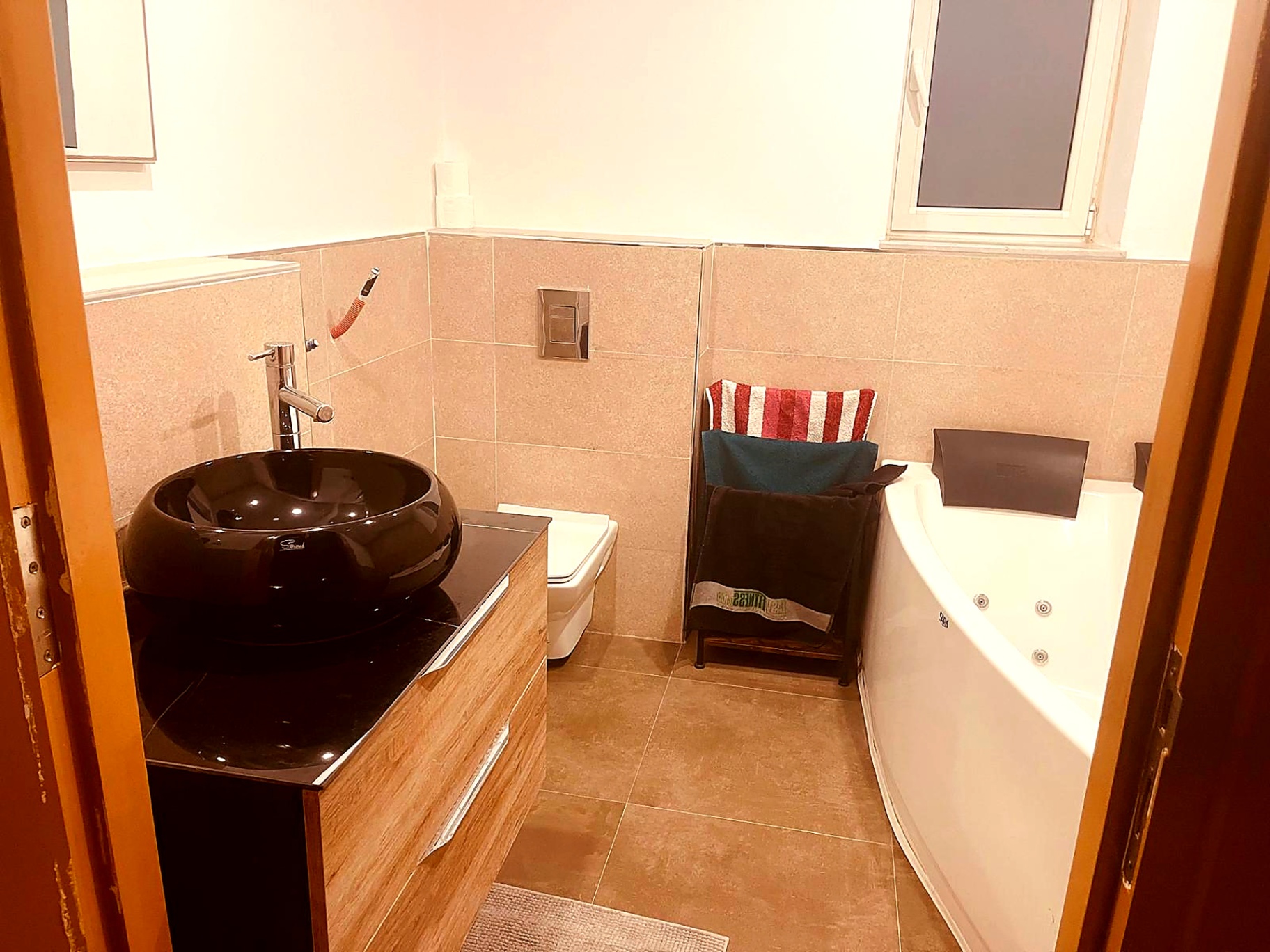 Bathroom with corner whirlpool bath and black stone basin