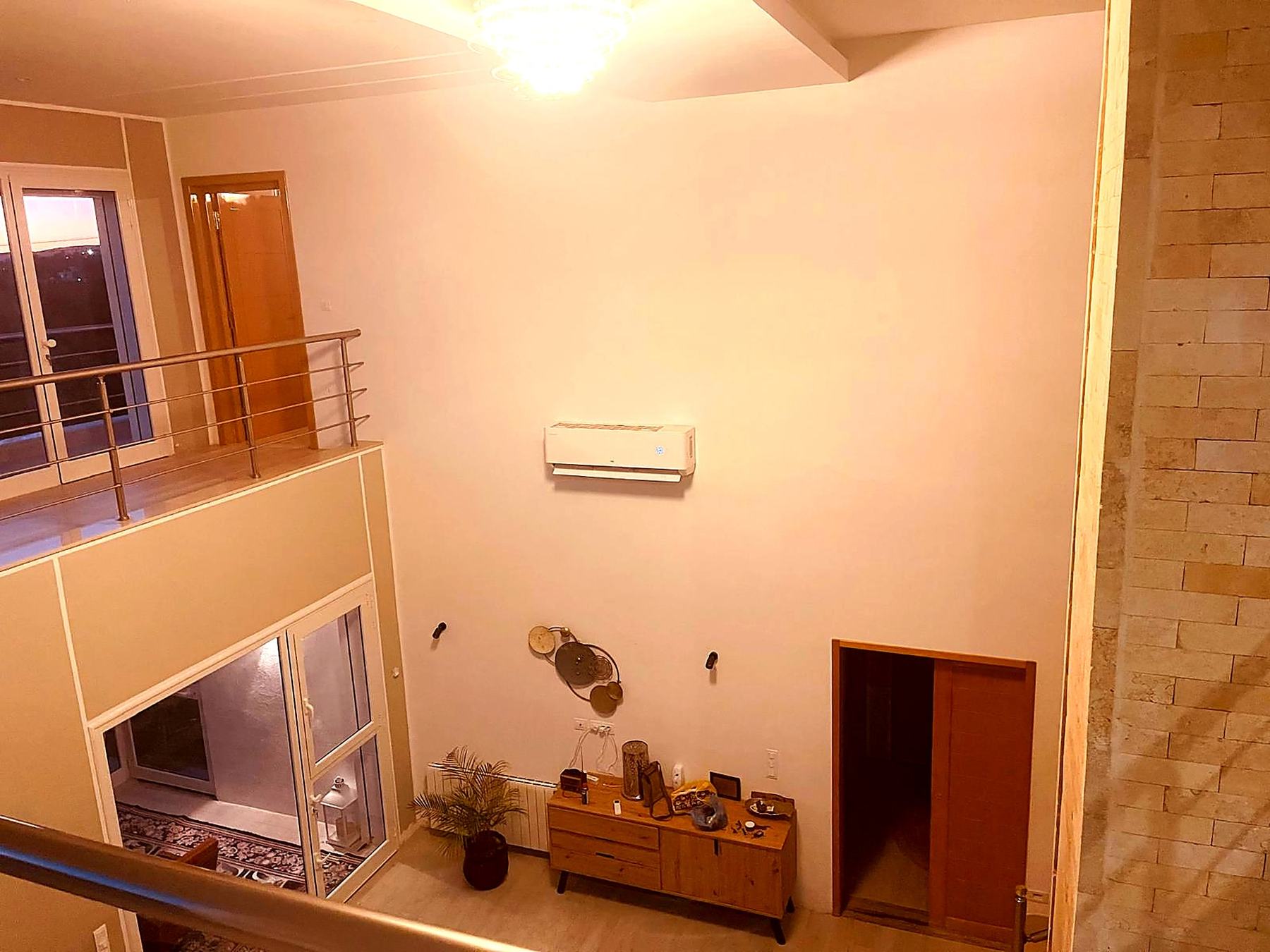 Double-height entrance hall with mezzanine and travertine wall
